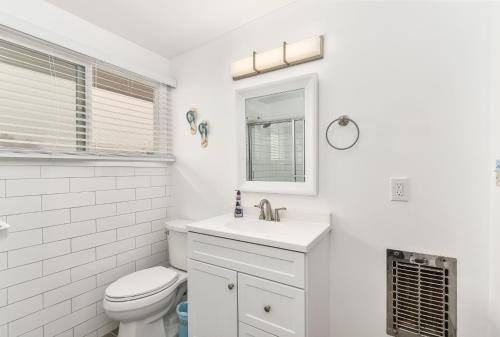 a white bathroom with a toilet and a sink at West Newport Duplex on the Sand with Patio-Sleeps 12 in Newport Beach