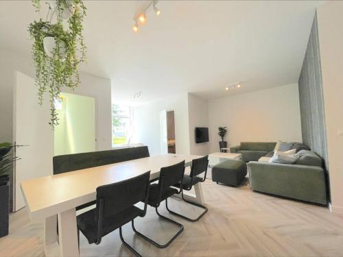 sala de estar con mesa, sillas y sofá en New Luxurious Apartment With 2 Bedrooms & Garden, en Roosendaal