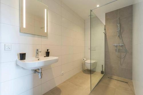 ein Bad mit einem Waschbecken und einer Glasdusche in der Unterkunft Oirschot 6c New Renovated Apartement in Oirschot