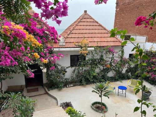 a house with pink flowers and a blue chair at Le Cabaoui in Poponguine