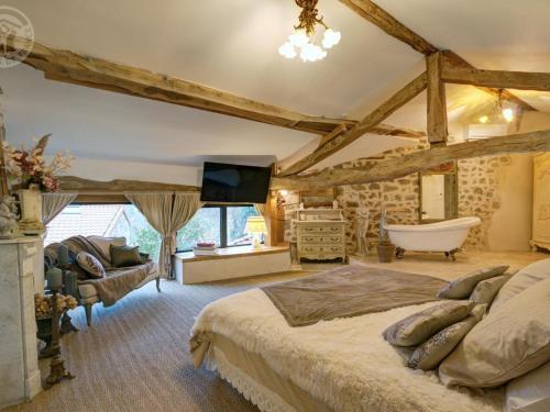 une chambre avec un grand lit et une baignoire dans l'établissement Gîte de Charme avec Piscine, Spa et Sauna, 5 Chambres, Jardin Privé et Équipements Modernes - FR-1-496-311, à Luré