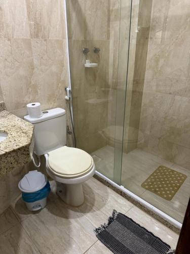 a bathroom with a toilet and a glass shower at Hotel Aconchego Da Vila in Saquarema