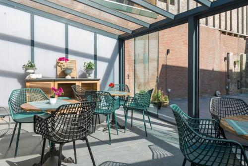 d'une terrasse avec des chaises, des tables et des fenêtres. dans l'établissement Room In The Center Of Tilburg Low Budget, à Tilbourg
