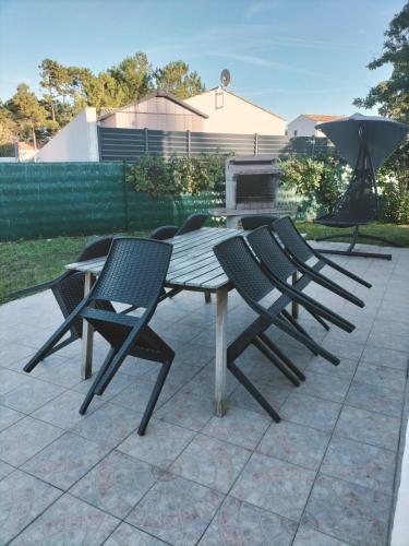 un groupe de chaises autour d'une table en bois dans l'établissement Maison calme proche mer - La Roseraie, à Saint-Hilaire-de-Riez