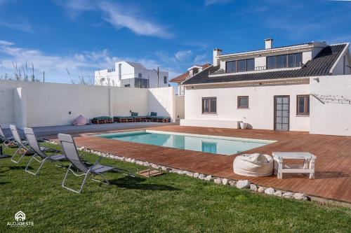 a backyard with a swimming pool and two chairs and a house at Palmeiras Beach House - Santa Cruz in Santa Cruz