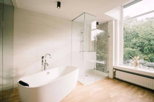 uma banheira branca na casa de banho com uma janela em Luxe Suite With Garden And Bath Sophie em Tilburgo