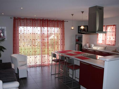 - une cuisine avec des rideaux rouges et un comptoir dans la chambre dans l'établissement Maison moderne proche de Chartres avec parking privé - FR-1-581-127, à Mignières