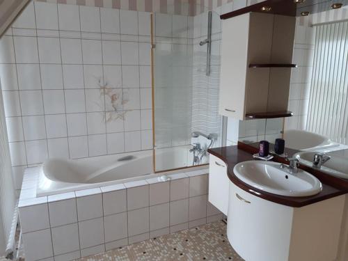 une salle de bain avec une baignoire et un lavabo et une baignoire dans l'établissement Maison familiale avec piscine chauffée, jardin et activités, 5 chambres, 10 pers, Merck-Saint-Liévin - FR-1-376-117, à Merck-Saint-Liévin
