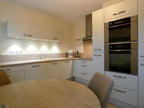 une cuisine avec une table et une cuisinière four supérieur dans l'établissement Appartement spacieux avec rooftop et garages privés à 3 min de la gare d'Épernon - FR-1-581-129, à Épernon