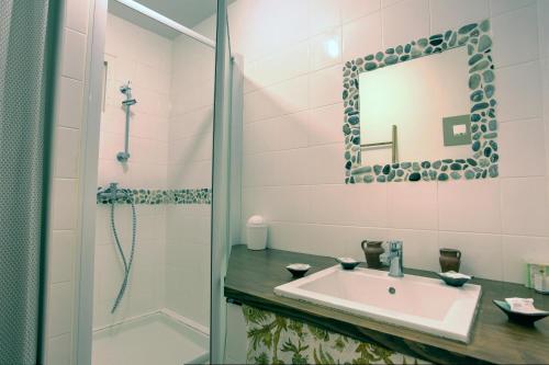 a bathroom with a sink and a shower and a mirror at Les Oliviers CENTURI-PORT in Centuri
