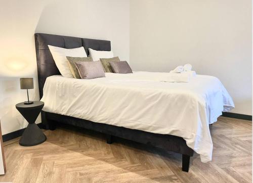 1 dormitorio con 1 cama grande con sábanas y almohadas blancas en Cozy Studio Unit With Kitchen & Bathroom, en Tilburg