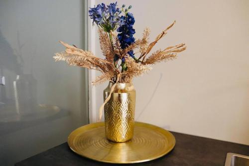 Eine goldene Vase mit blauen Blumen auf dem Tisch. in der Unterkunft Stadsvilla Luxious Koetshuis New in Tilburg