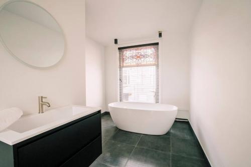 a bathroom with a tub and a sink and a mirror at Large Apartment With 2 Bedrooms Stadsvilla in Tilburg