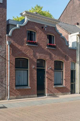 a red brick building with two windows and a door at Cozy suite with new shower near Popodium 013 in Tilburg