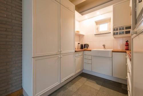 uma cozinha com armários brancos e um lavatório em Stunning Catena Property em Boxtel