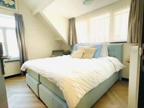 duże łóżko w pokoju z oknami w obiekcie Lovely Suite Newly Renovated w mieście Tilburg