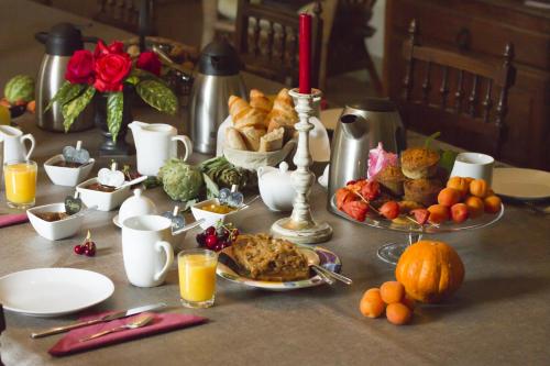 una mesa con desayuno de comida y zumo de naranja en Maison d'hôtes de Charme Les Bruhasses, en Condom