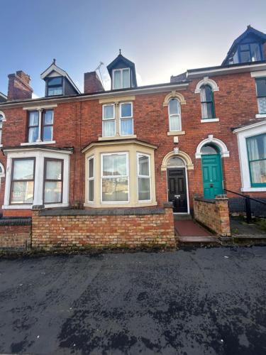 a brick house with a green door on a street at Mill Hill Stays in Derby