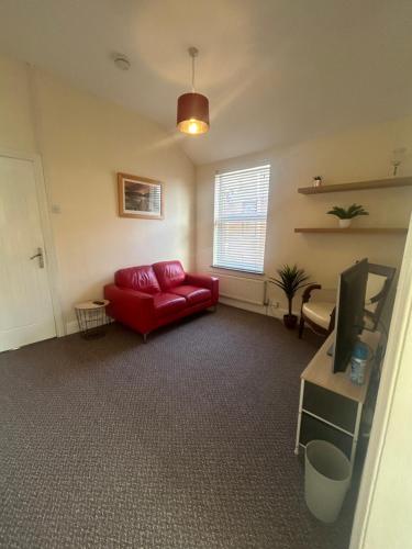 a living room with a red couch and a tv at Mill Hill Stays in Derby