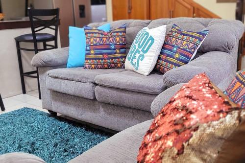 a living room with a gray couch with colorful pillows at Travelholics Getaways in Piarco