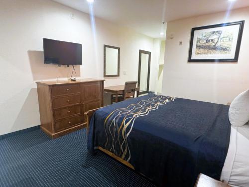 a hotel room with a bed and a desk and a television at Pecan Valley Inn & Suites in San Antonio