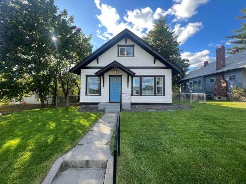 a white house with a blue door in a yard at Renovated 3bd 1bth Home in North Spokane Near DT in Spokane