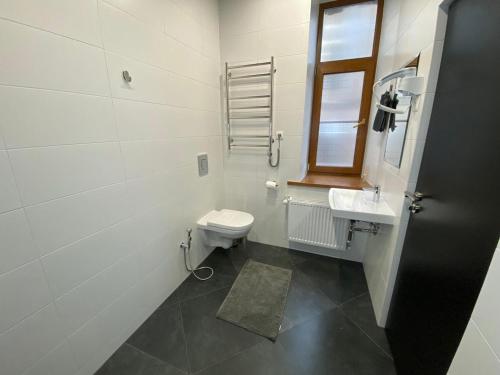 a white bathroom with a toilet and a sink at ApartHotel Riga in Rīga