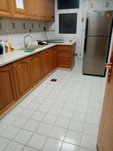 a kitchen with a refrigerator and a white tile floor at A103 Cozy Private Room Shared Apartment Muroor Abu Dhabi UAE in Abu Dhabi