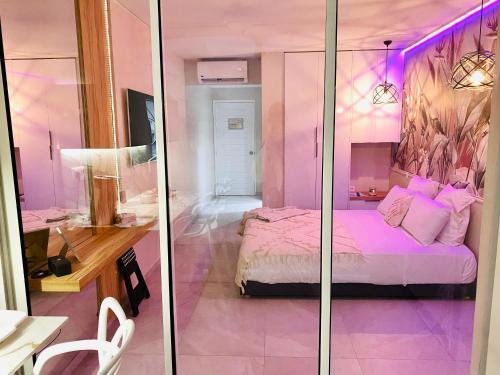 een roze kamer met een bed en een bureau bij Diadora au magnifique panorama - Studio neuf de prestige vue mer in Le Diamant