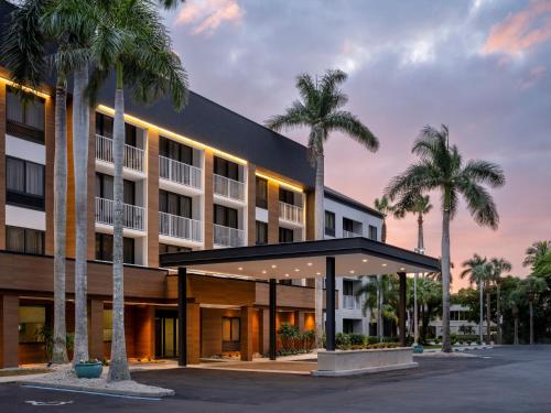 an exterior view of a hotel with palm trees at Courtyard by Marriott - Naples in Naples