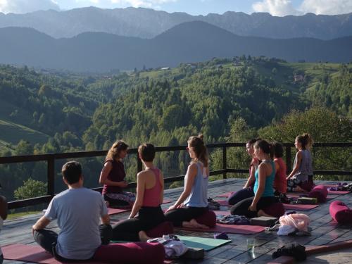 un groupe de personnes assises dans une pose de yoga dans les montagnes dans l'établissement Akasha Retreat - Nature, Yoga & Wellness, Healthy Food & Drinks, à Peştera