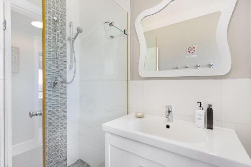 a white bathroom with a sink and a shower at Witsand 804 by Host Agents in Bloubergstrand