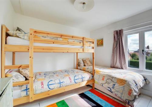 two bunk beds in a room with a window at BackToFront Cottage in Briston