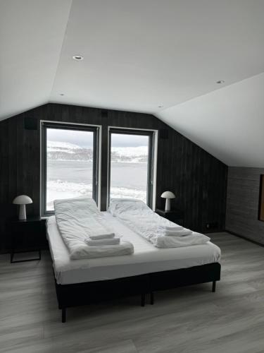 a large bed in a room with two windows at Arctic Sea Breeze in Kirkenes