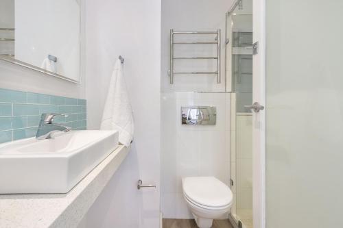 a white bathroom with a sink and a toilet at Portico 704 in Bloubergstrand