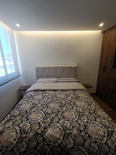 ein Bett in einem kleinen Zimmer mit einer Decke drauf in der Unterkunft Apto 1008 RB Increíble inmueble in Tunja