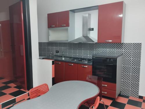 een keuken met rode kasten, een tafel en een fornuis bij 0823 caserta centro in Caserta