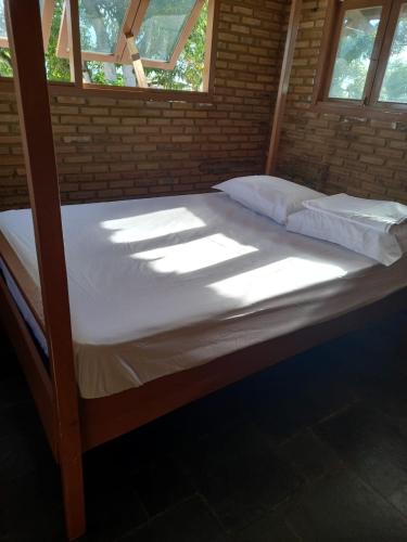 ein großes Bett in einem Zimmer mit einigen Fenstern in der Unterkunft Chacara Delfino in Indiaroba