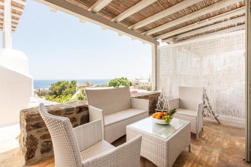 a patio with wicker chairs and a table on a balcony at Villa Azallea by Mykonian Kazarte in Kalafatis