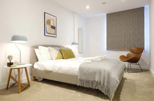 a white bedroom with a bed and a chair at 2 Bedroom 2 Bathroom Cosy Apartment - Zone 1 - Central London in London