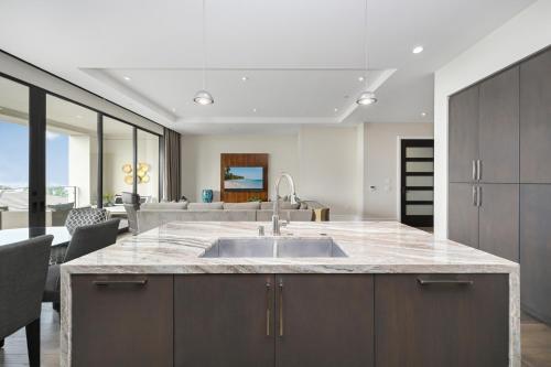 a kitchen with a sink and a living room at True Luxury Living in Fashion Island with Elevator and Ocean Views in Newport Beach