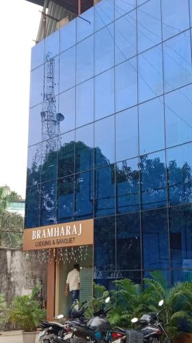 a glass building with motorcycles parked in front of it at New Bramharaj By Glitz Hotels in Navi Mumbai