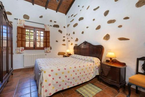um quarto com uma cama e uma parede com pedras em 2 bedrooms villa with private pool terrace and wifi at Vega de San Mateo em Vega de San Mateo
