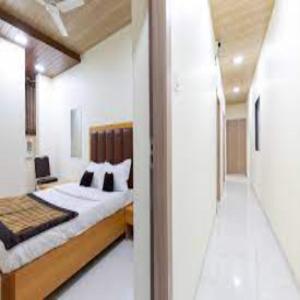 um quarto com uma cama grande e um corredor em New Bramharaj By Glitz Hotels em Navi Mumbai