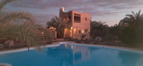 a house with a swimming pool in front of a building at La Siwa in Siwa