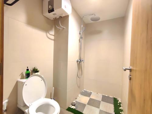 a small bathroom with a toilet and a shower at Furnished Studio, 5 mins to LRT Jabodebek Station in Kaliastana