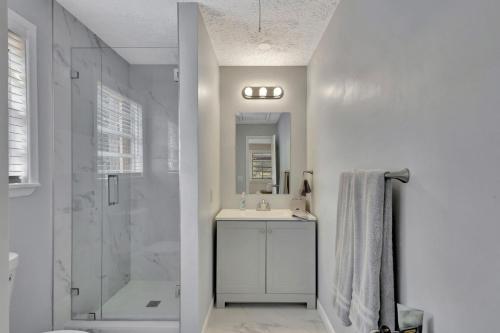 La salle de bains blanche est pourvue d'un lavabo et d'une douche. dans l'établissement 2 BR Jensen Beach Tropical Resort, à Fort Pierce