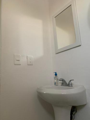 a white bathroom with a sink and a mirror at CASA JARDIN in Cancún