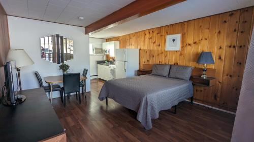 a bedroom with a bed and a table and a kitchen at Deerview Lodge & Cabins - Princeton BC in Princeton