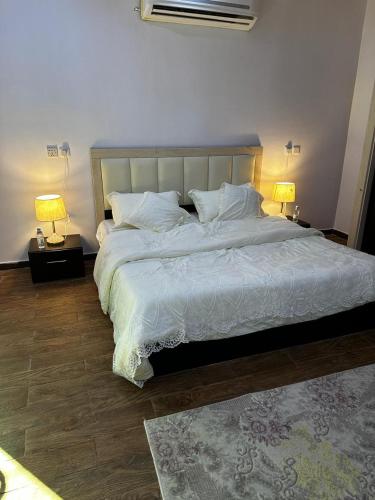 a bedroom with a large white bed with two lamps at مبيت نسيم الجبل in AlUla